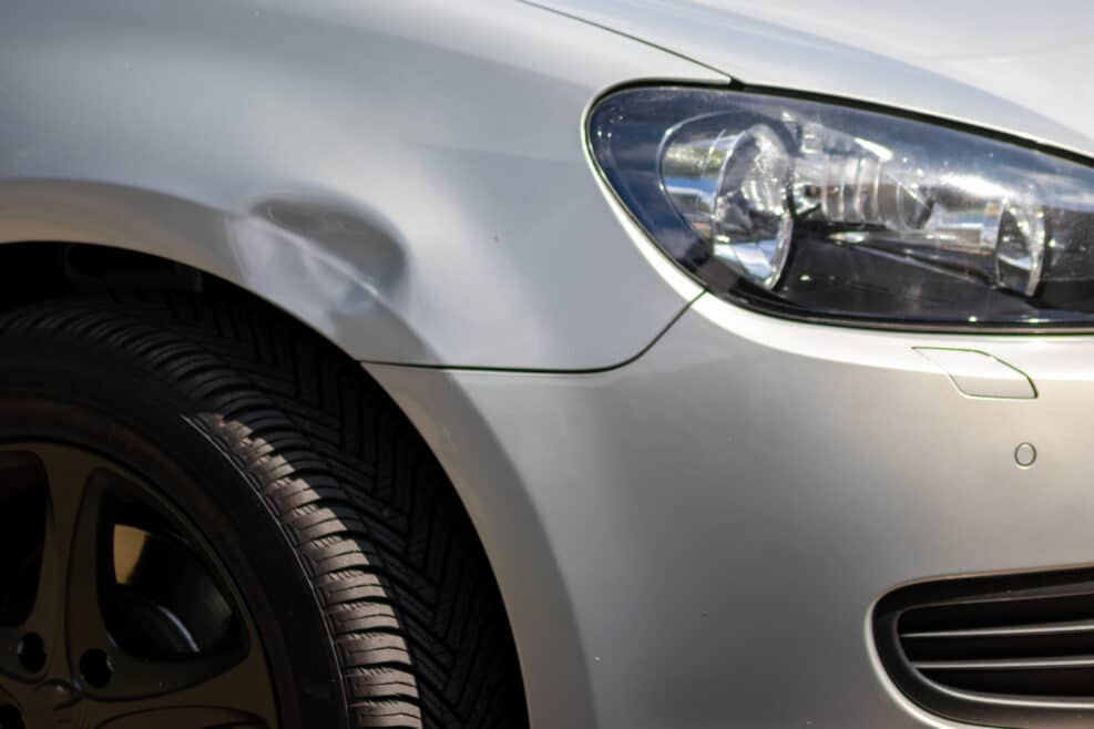 Dented car wing and fender with scratches and bumps after crash and car accident with hit-and-run driving and absconding shows need for car insurance and safety protection and mechanics garage service