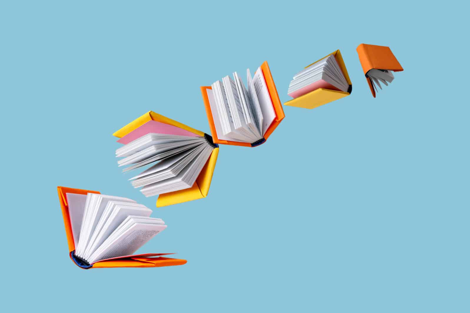 books in colored covers swirl on a blue background, copy space