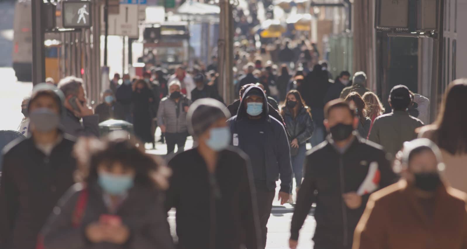 Anonymous crowd of people walking street wearing masks during covid 19 coronavirus pandemic in New York City November 2020