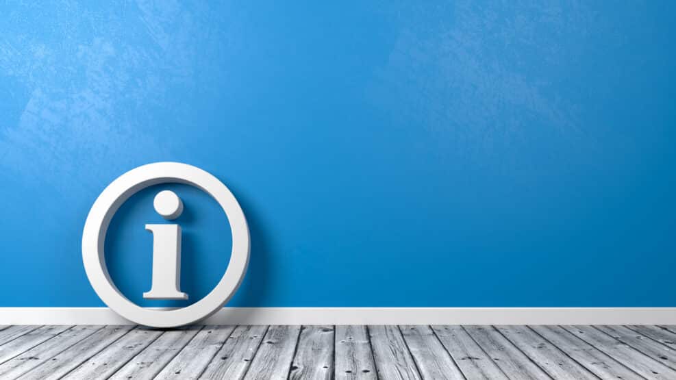 Information Symbol on Wooden Floor Against Wall