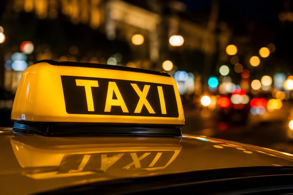 taxi sign on car roof at night city lights